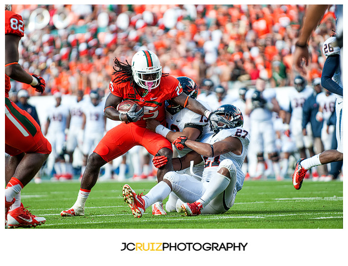 Hurricanes RB #25, Dallas Crawford, tries to elude tacklers from Virginia