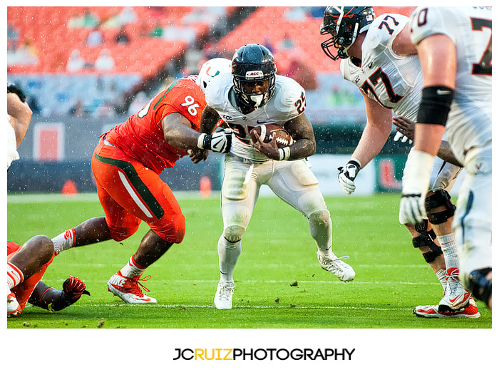 Virginia RB, #25 Kevin Parks, tries to elude the tackle of Hurricanes #96, Curtis Porter