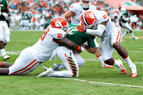 Miami Hurricanes QB #12, Malik Rosier, gets sandwiched by two Clemson defenders