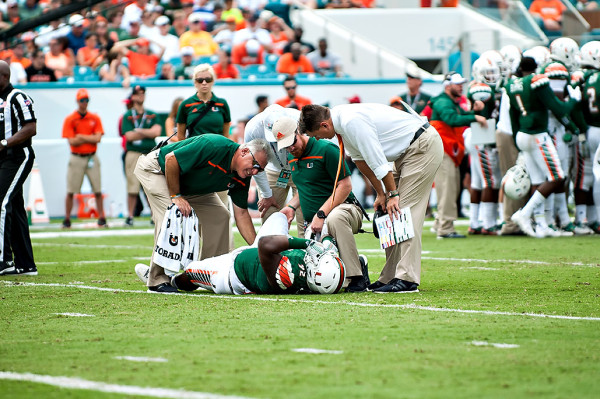 Miami head coach, Al Golden, looks in on injured player #92, Courtel Jenkins