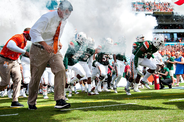 The Miami Hurricanes run through the smoke