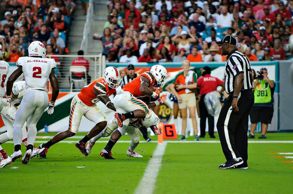 Hurricanes RB, Mark Walton, leaps over a defender for the endzone