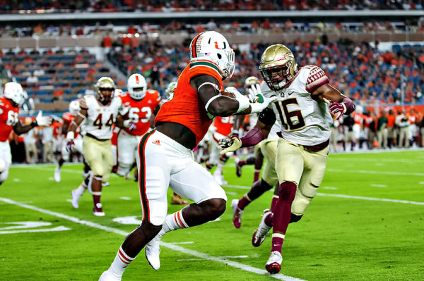 Hurricanes TE, David Njoku, extends a stiff arm on Florida State LB, Jacob Pugh