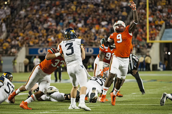 Miami Hurricanes DL, Chad Thomas, deflects a pass from West Virginia QB, Sklyer Howard
