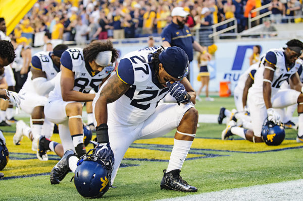 Sean Walters, West Virginia LB, takes a knee in prayer before the game