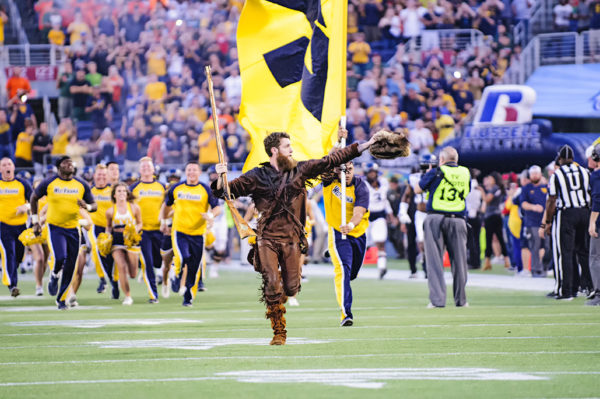 The West Virginia Mountaineers mascot leads the team onto the field