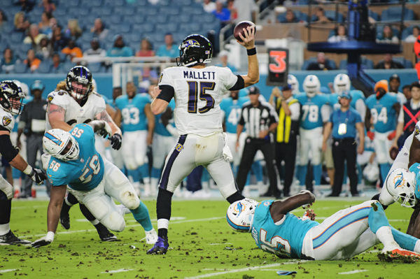 Ryan Mallett, Ravens QB #15, throws the ball under pressure from the Dolphins defense