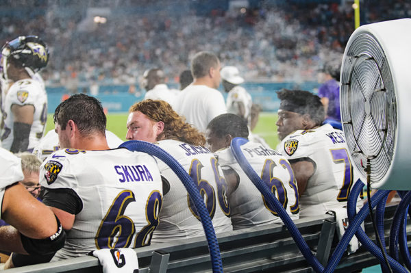 Ravens players cool off by sticking cold hoses down their jerseys