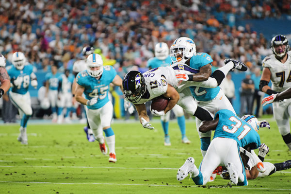 Ravens WR #12, Michael Campanaro, gets tackled mid-air by Dolphins S #22, T.J. McDonald
