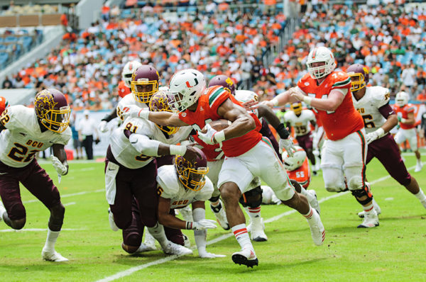 Hurricanes RB, Travis Homer extends a stiff arm to a defender