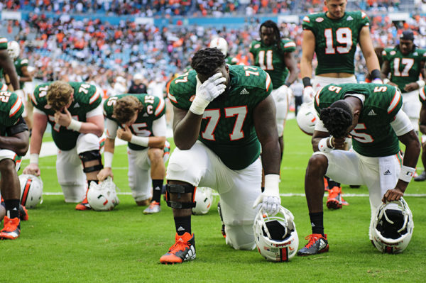 Players take a knee for prayer before the game