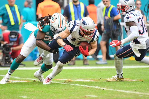 Miami Dolphins defensive back Walt Aikens (35) tackles New England Patriots wide receiver Julian Edelman (11)