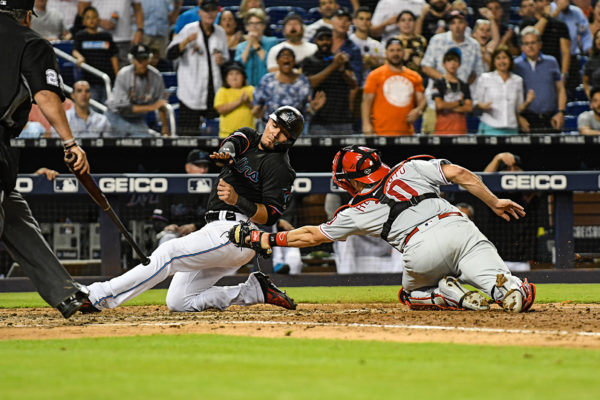 Miami Marlins shortstop Miguel Rojas (19) slides past the tag of Philadelphia Phillies catcher J.T. Realmuto (10)